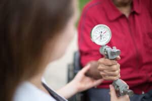 Person in red shirt holding rehab tool with medical professional hands helping.