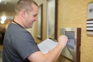 Medical professional entering information on a wall screen outside a patient room.