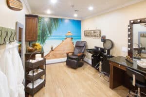 Beauty shop with bath robes, sink, lit mirror, and tropical mural.