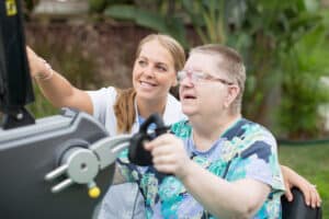 Man using rehab machine with medical professional in white jacket next to him helping him.