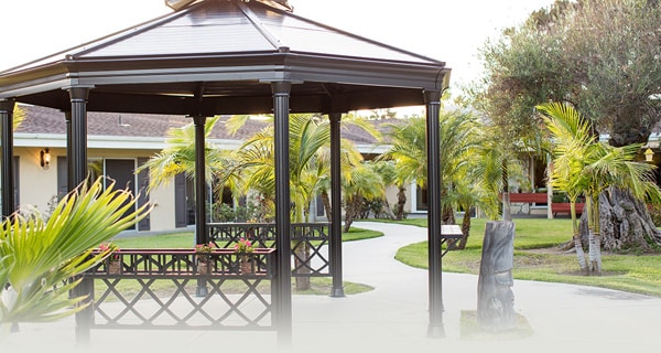 Pergola, walking paths, trees, and green grass at La Paloma Healthcare Center