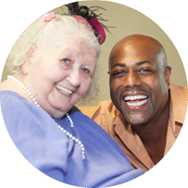 elderly resident and caregiver smiling together
